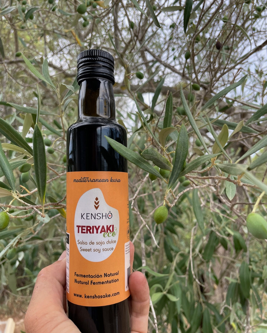 Bottle of Kensho Teriyaki sauce held in front of an olive tree